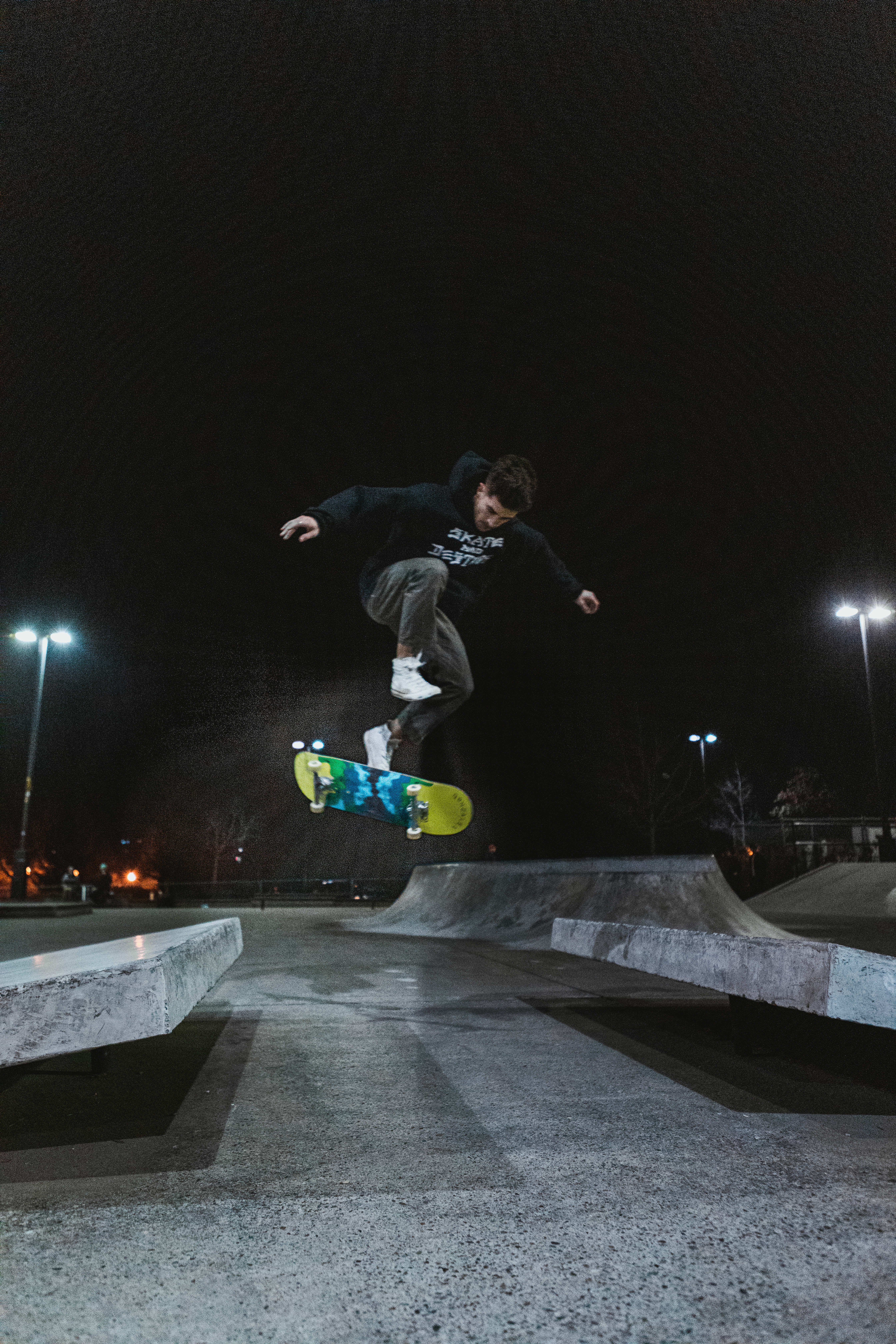 Skater mid-kickflip at the park at night