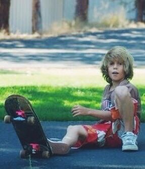 Young kid sitting with a skateboard
